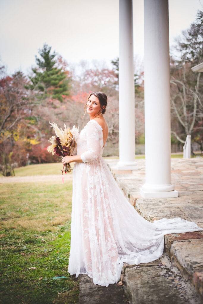 bride posing with flowers in front of white columns