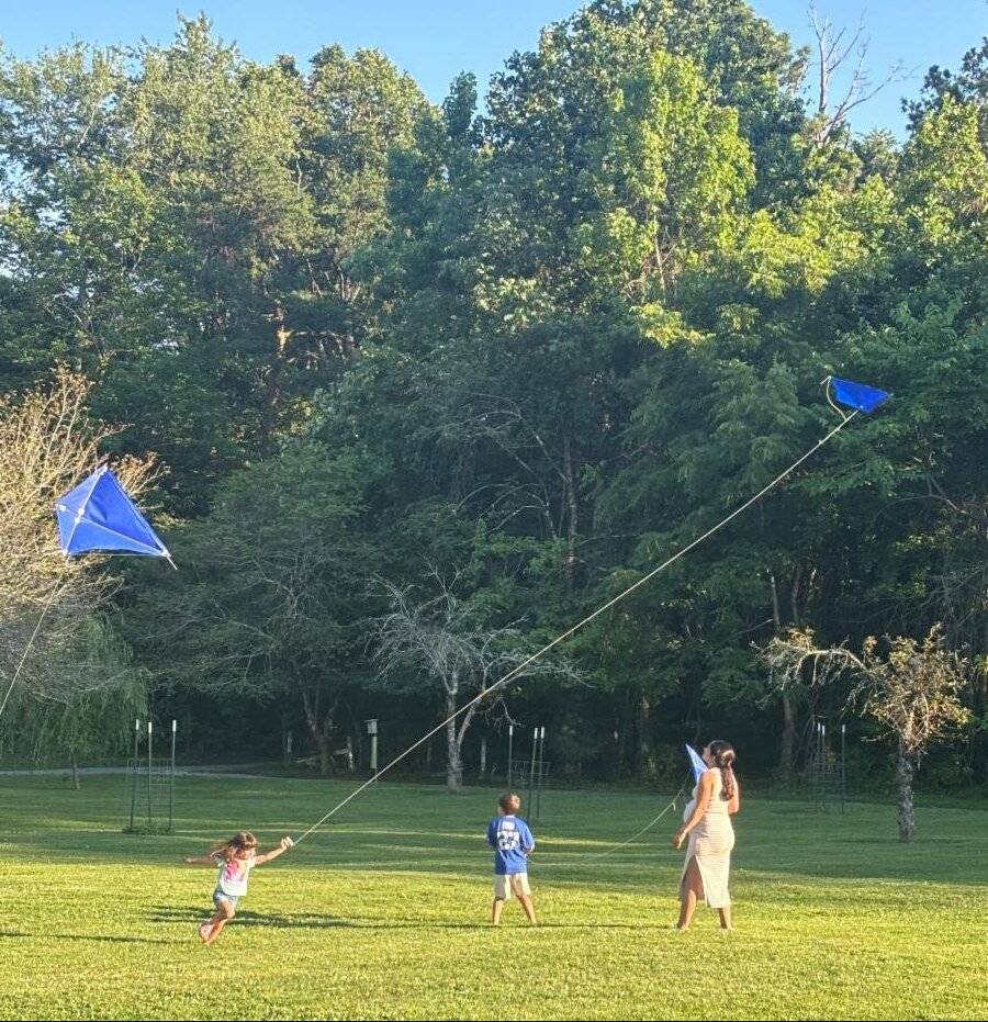 A family flying blue kites in a field at McCoy Farm and Gardens